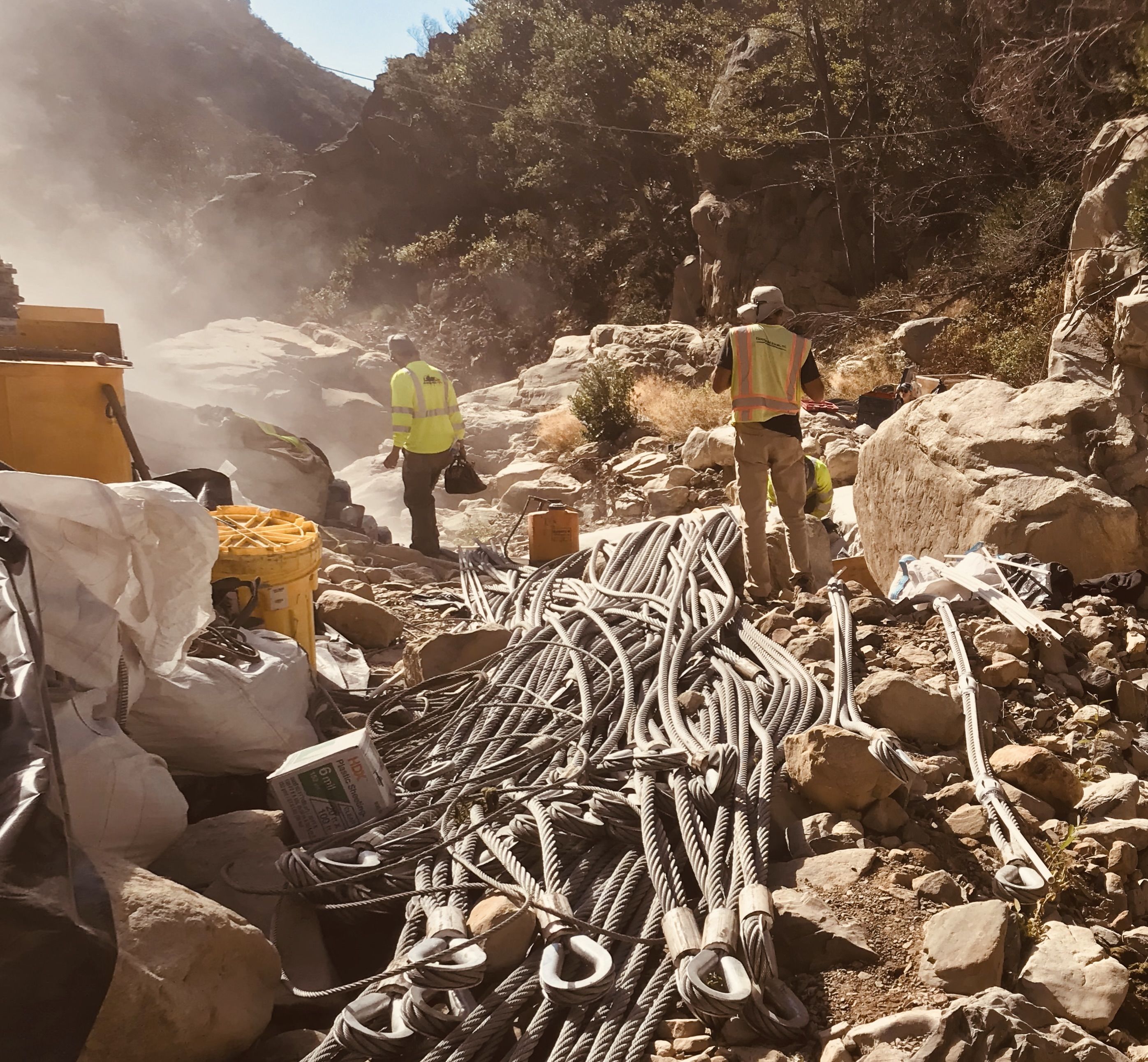 3 members of The Project for Resilient Communities adding steel mesh nets over large and small boulders to capture debris in high-risk areas.